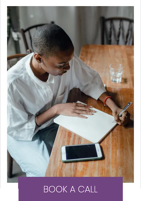 Woman at desk writing on pad of paper