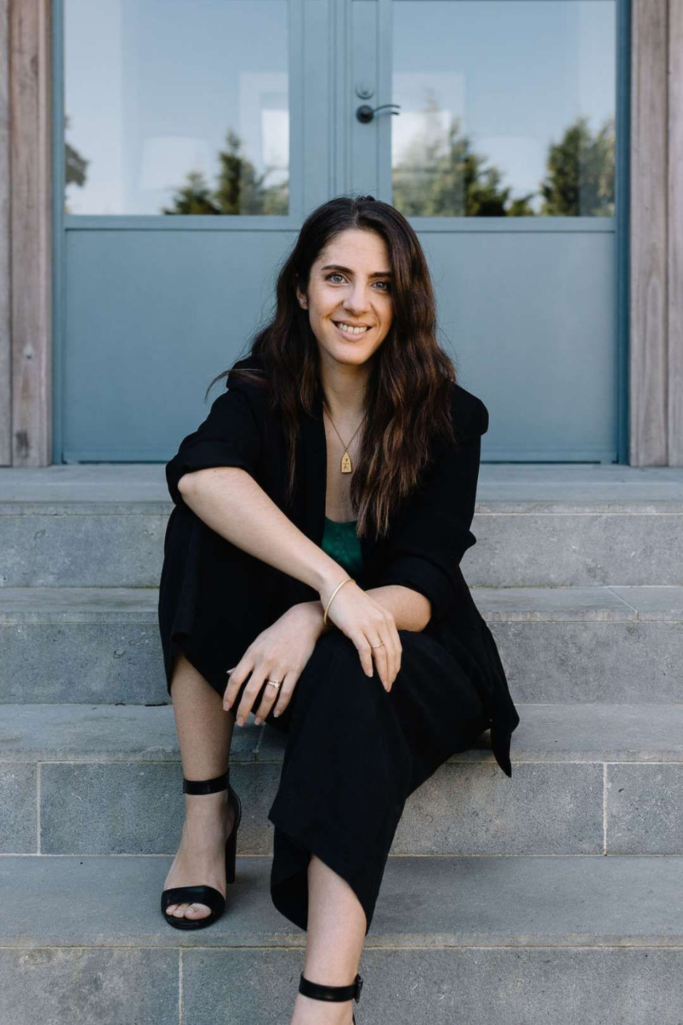 Hareta sitting on outside steps smiling at camera with arms casually crossed over legs