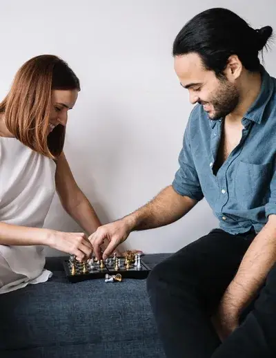 Man and woman sitting on bench playing chess on a small chessboard