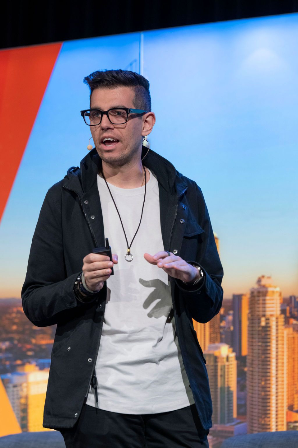 A man (Theo Kapodistrias) standing in a collared shirt, and wearing glasses looking into the distance