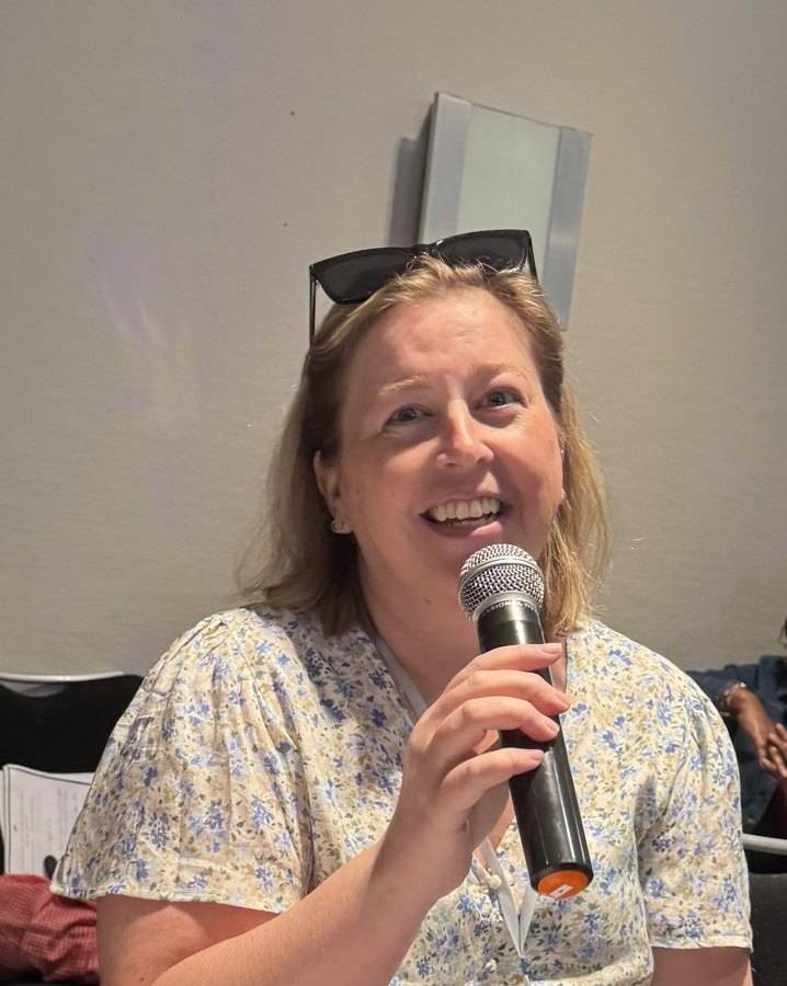Becca Gerlach, LMSW, speaking into a microphone during a mental health conference session on burnout and unmasking