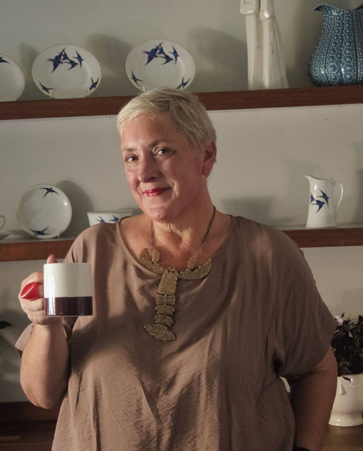 Nicola Lutz, founder of No Fluff consultancy, standing in a kitchen holding a coffee cup, smiling confidently.