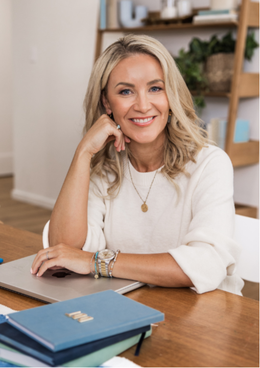 Woman sitting on window sill with laptop in her lap