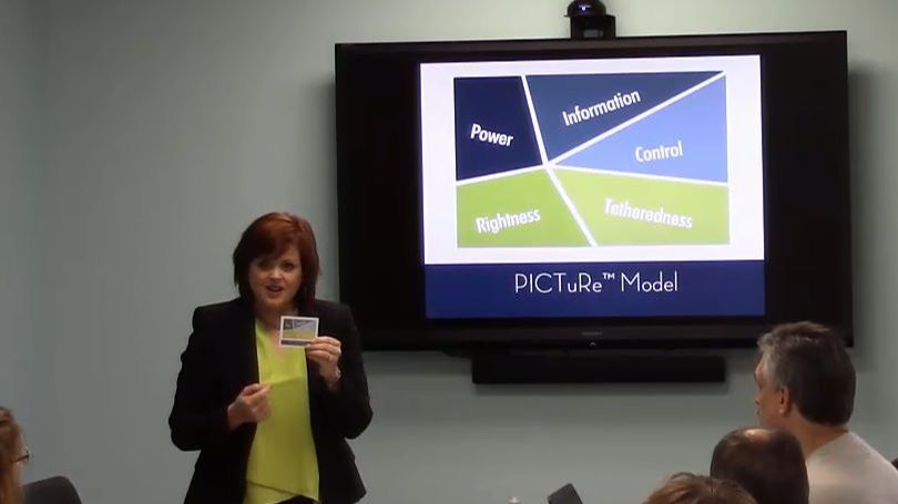 Dr Erika Salina sitting on wooden stairs, in a copper blazer, smiling big at the camera