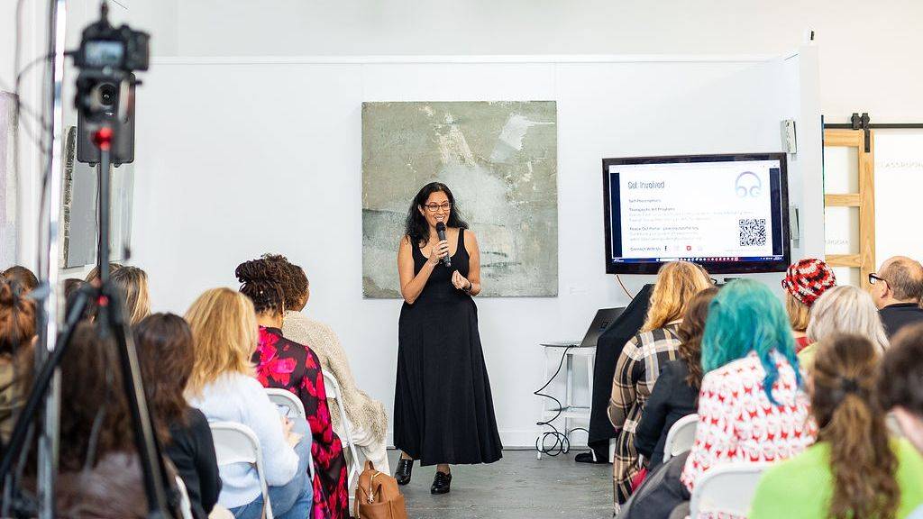 Candid photo of Sheetal holding a microphone while speaking to an audience