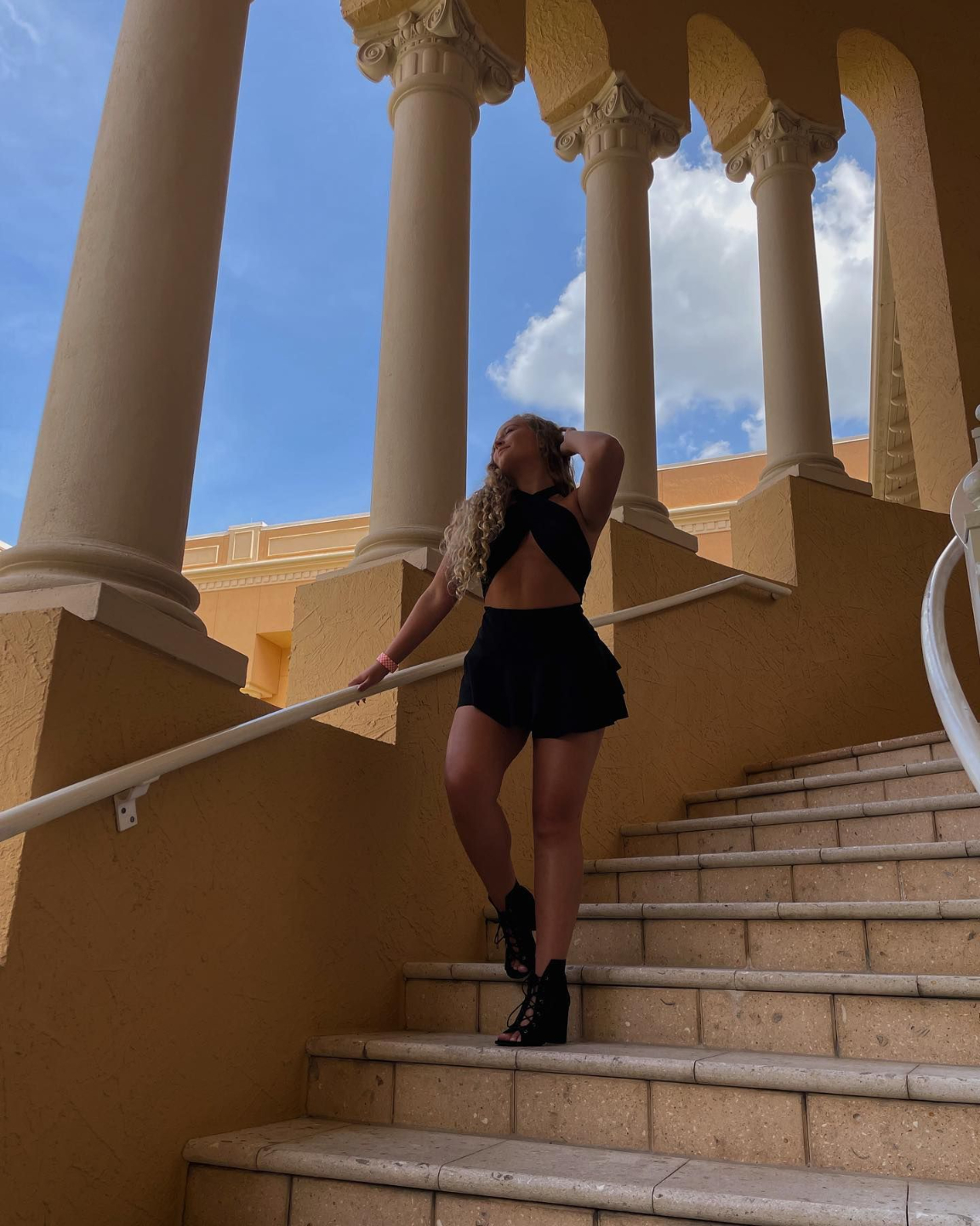 Lili Rose Zayak woman on stairs roman architecture Ritz JW Marriott Hotel Resort Summer Fashion Black Dress