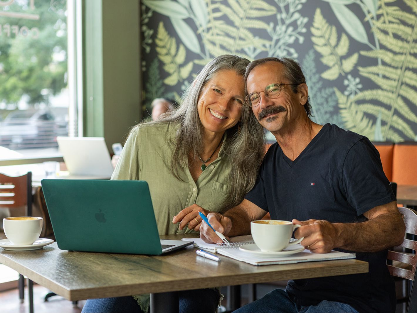 Steph and Lane French in a cafe on their laptop