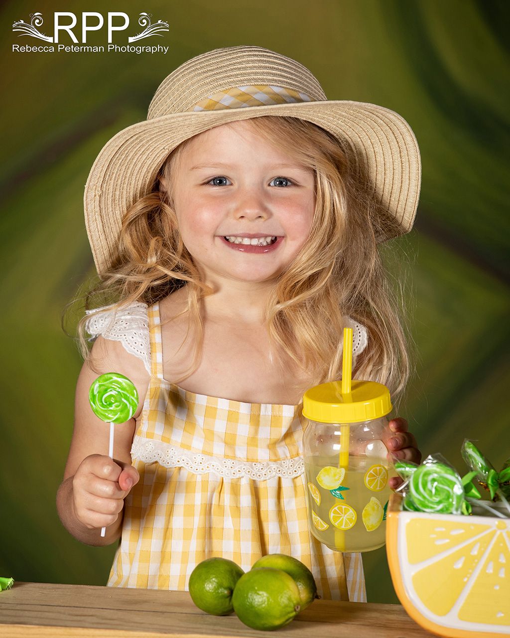 preschool girl blond hair straw hat yellow checked dress holding glass lemonade green sucker