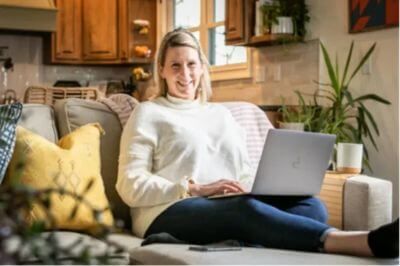 Katy Poole sitting on a couch using a laptop for fertility wellness support