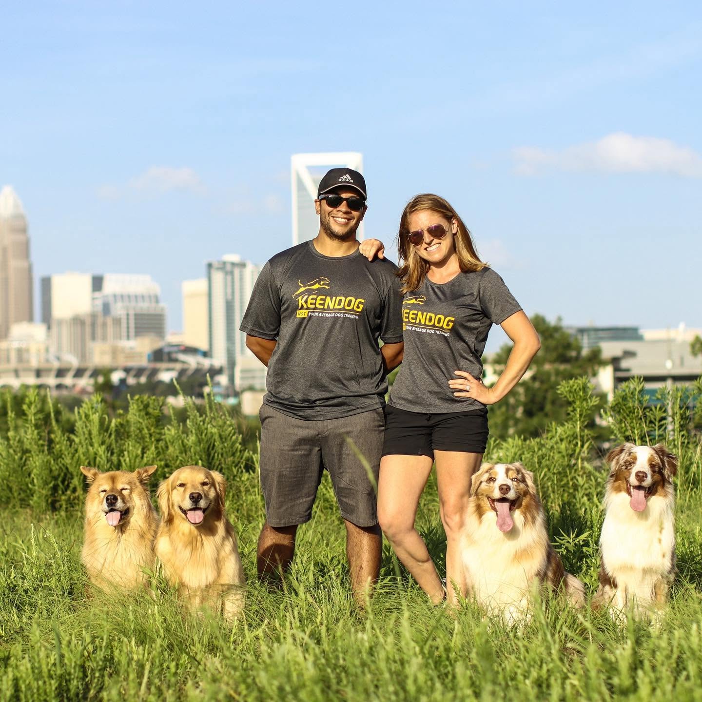 KeenDog founders standing in grassy field in Charlotte, NC surrounded by 4 dogs