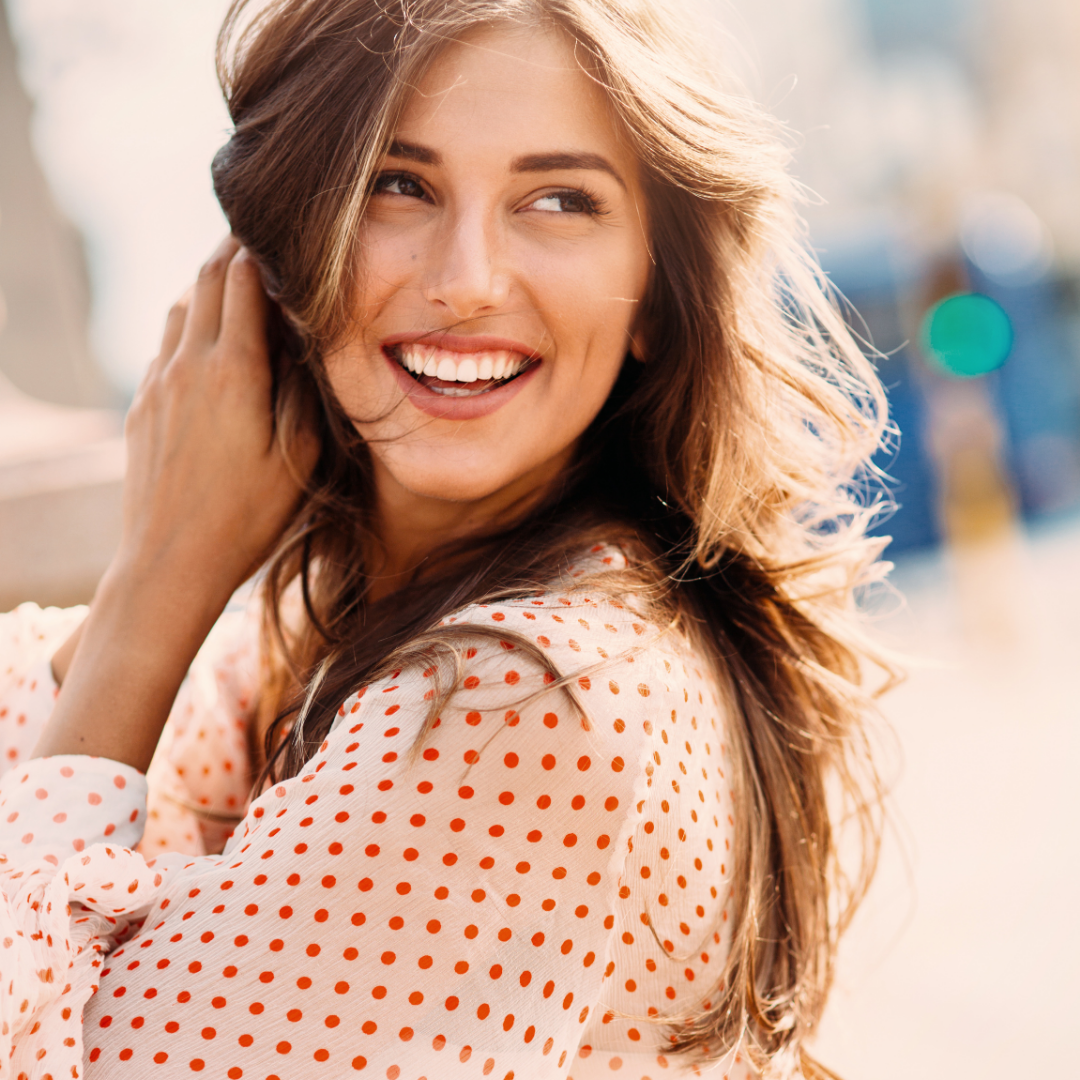 Laughing, happy woman in a white and pink spotted shirt