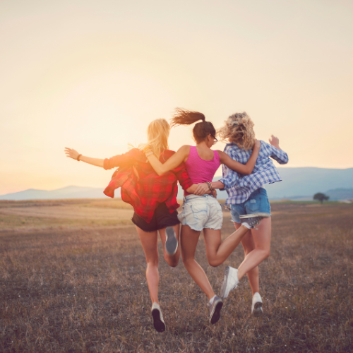 3 young women linking arms and skipping for joy
