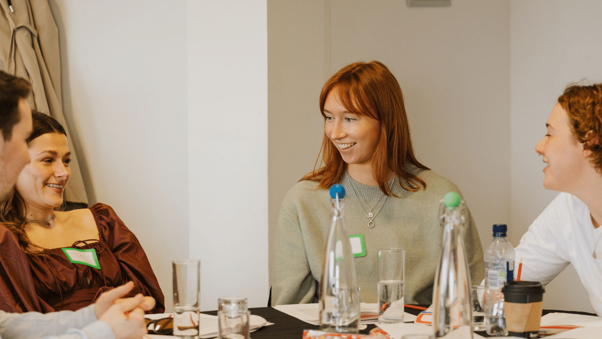 Image of three young women taking part in a workshop, smiling and sharing ideas. 