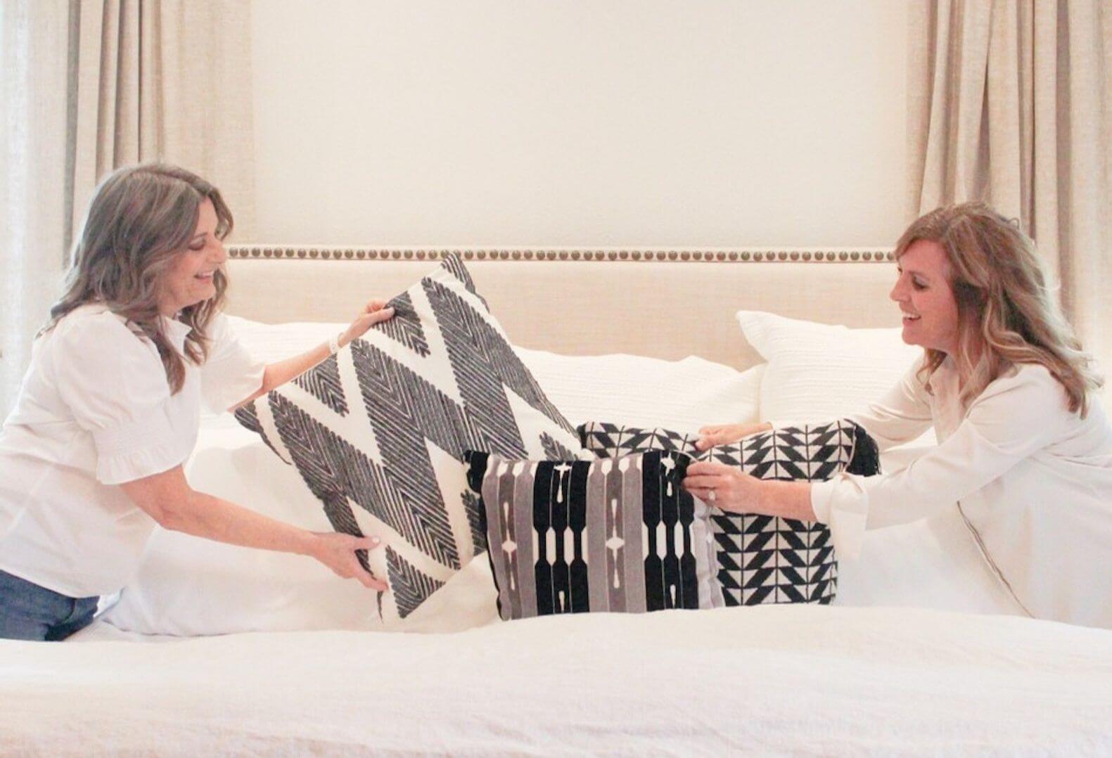 Staging Studio Co-Founders Debbie Boggs and Julie Young style a bed with pillows