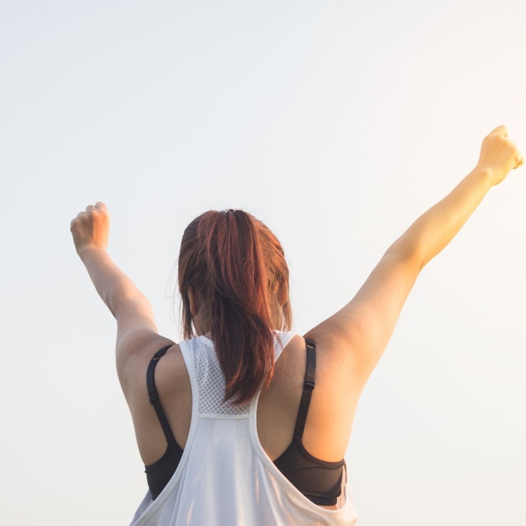 Woman with arms raised celebrating a healthy hormones and skin.