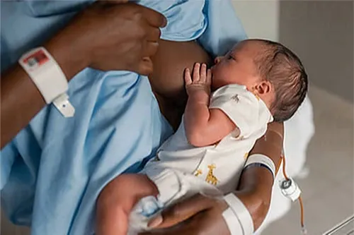 Black woman nursing newborn baby