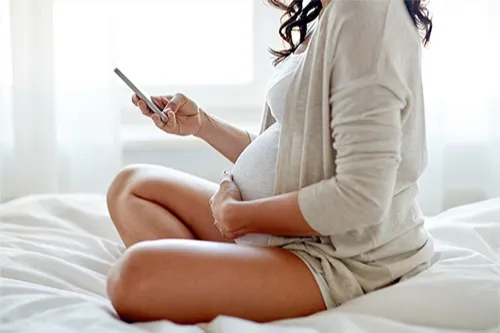 Pregnant woman on mobile phone holding belly