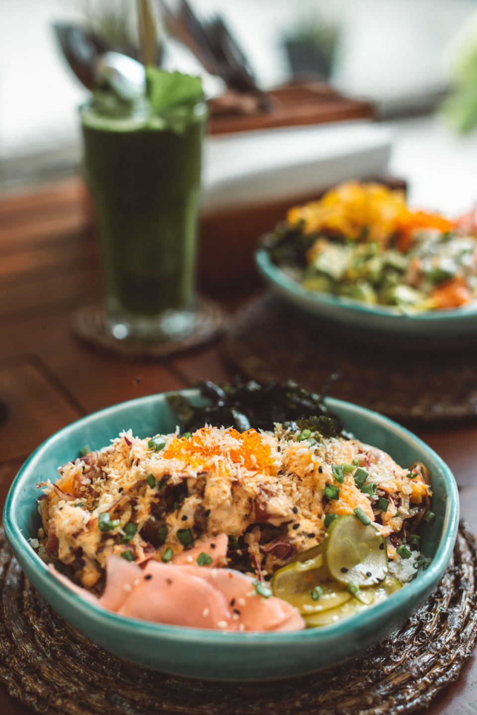 Bloat and Gut Health nourishing green smoothie with two asian poke bowls filled with pickled gingers, rice, nori sheets and green vegetables.