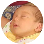 A peaceful sleeping baby, lying on their back with closed eyes and tiny hands resting on their chest.