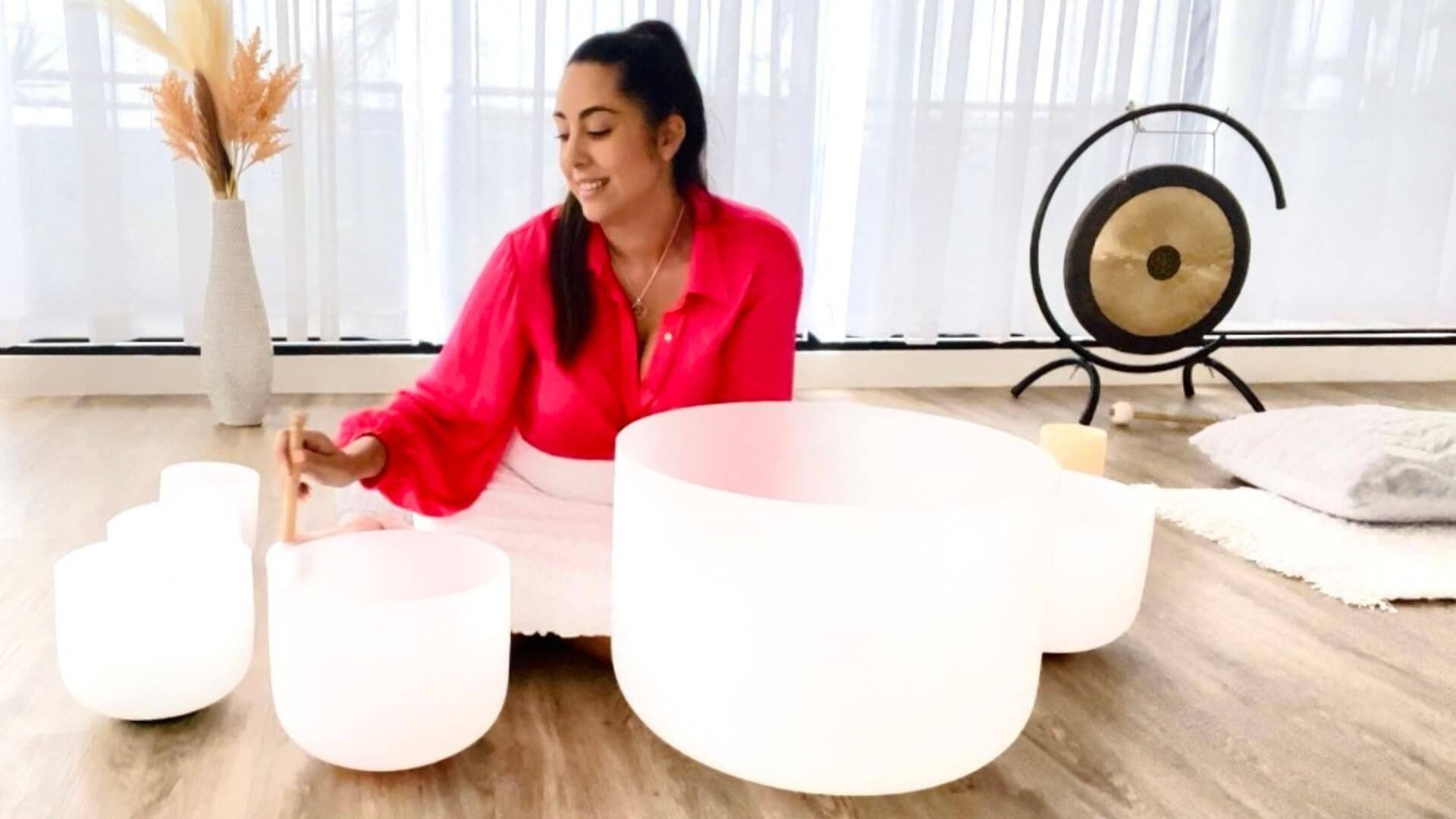 Practitioner striking a crystal singing bowl with a mallet during a sound healing session