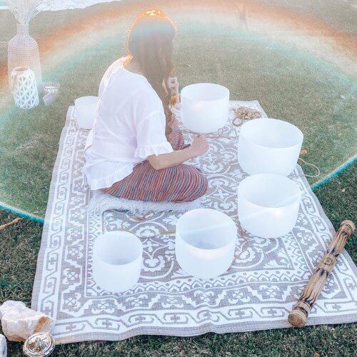 Crystal singing bowls arranged for an outdoor sound healing meditation in a peaceful garden setting
