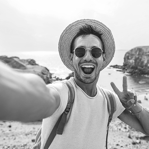 man on the beach smiling and giving the peace sign. He is living his best life free from back and hip pain.