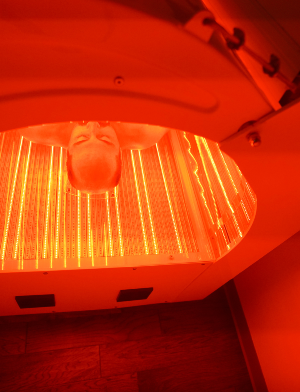 Man laying in a red light bed with the red lights on at Evergreen Factor in Oregon, experiencing the rejuvenating benefits of red light therapy for enhanced well-being and relaxation.