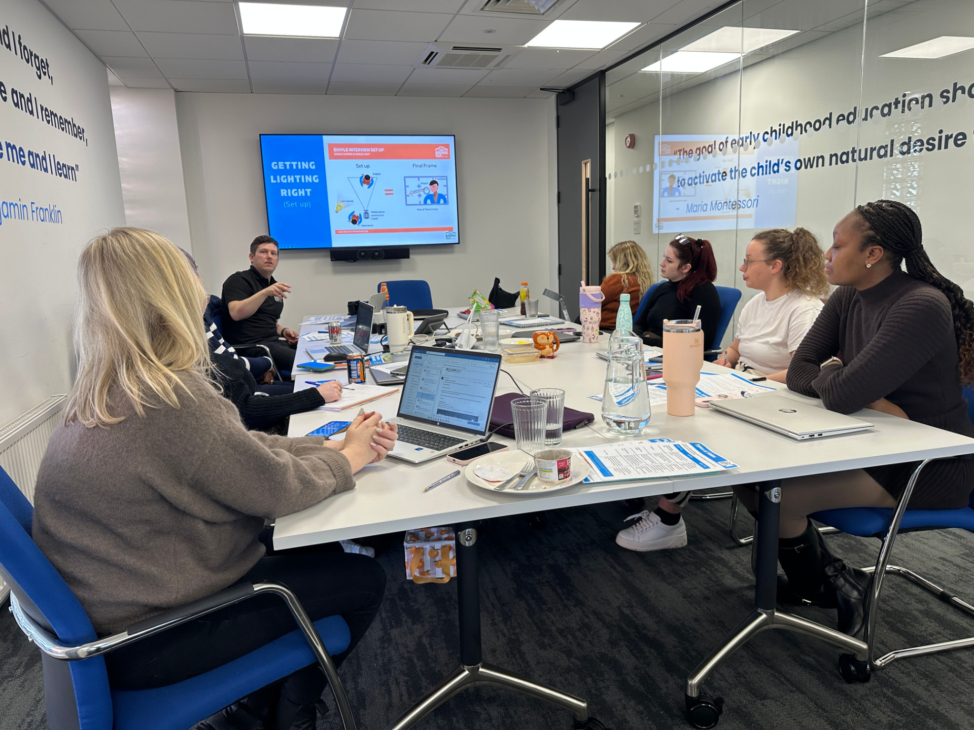 People sitting at a table in a training workshop learning how to use their smartphones to make business videos.