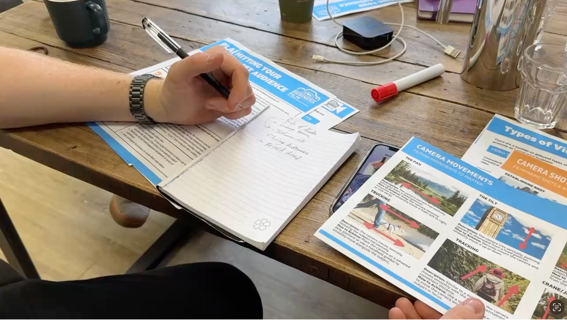 Business owner filling in a video planning worksheet during a practical smartphone video training session.