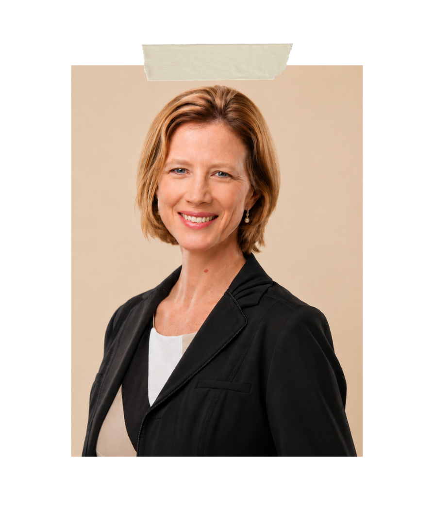 Studio portrait of Serenely Rooted founder smiling in a black blazer against a plain brown background, representing intentional home systems, family organization, and empowered motherhood.