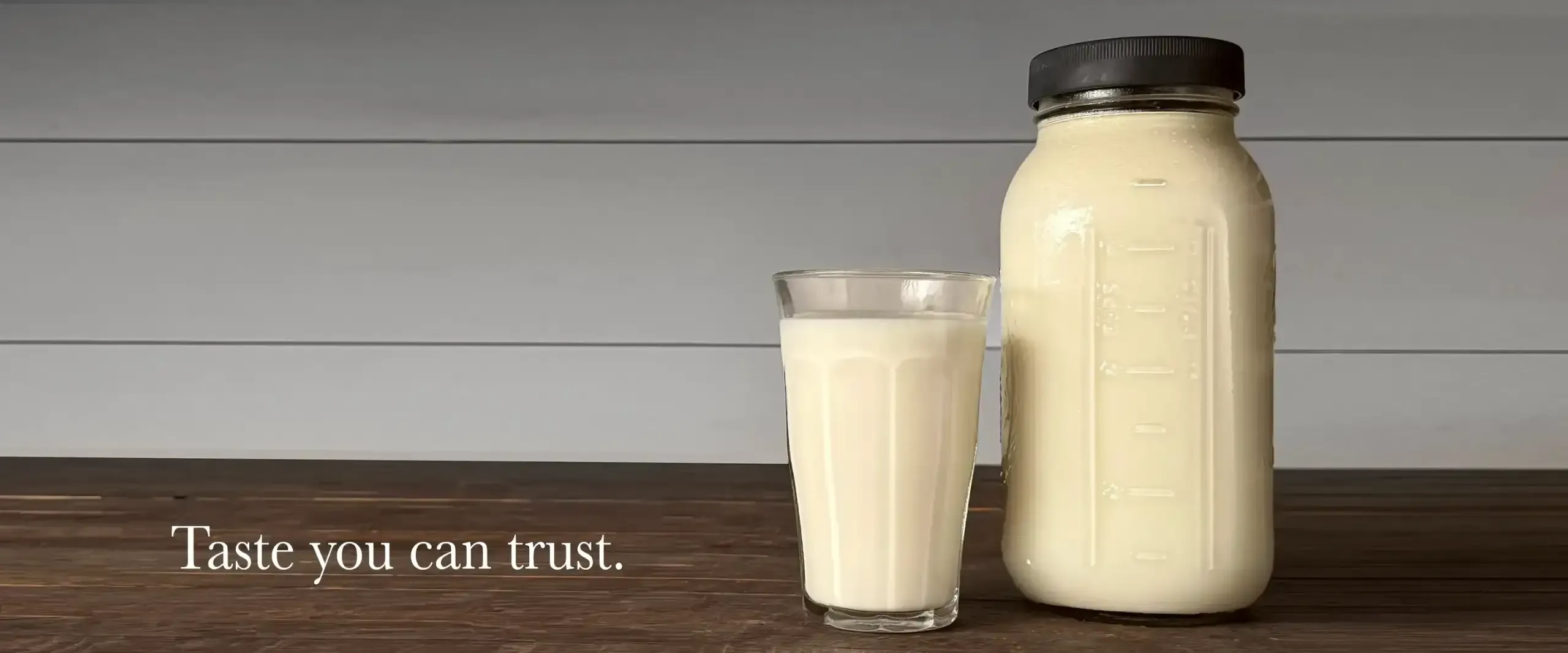 Raw milk in glass and jar on wooden table, produced by Dexter cows at Mountain Heritage Farm, Cannon County, Tennessee.