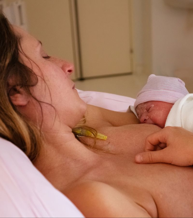 Newborn baby in new mother's hands after giving birth in the hospital