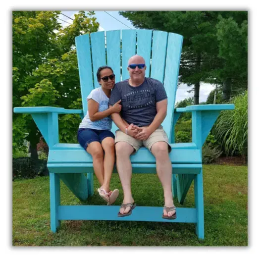 Doug Collins and his wife seated on an oversized blue Adirondack chair, showcasing the balance and joy from the Feel Great System.