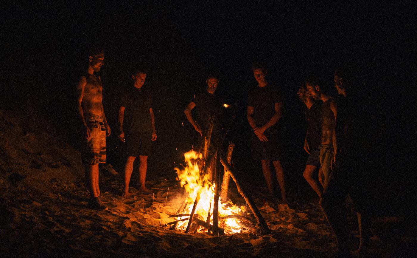 Group of young men gathered around a bonfire