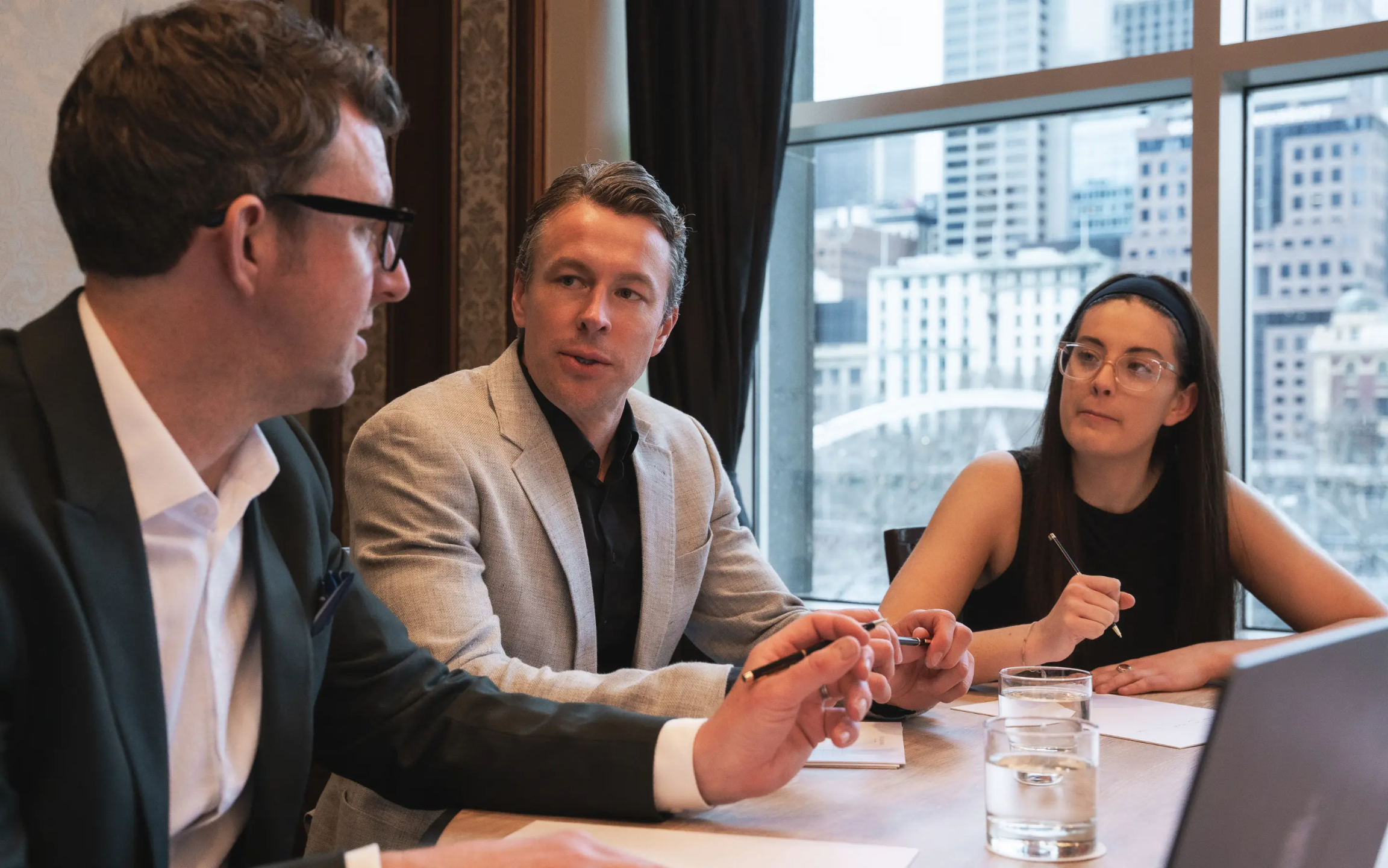 Three people sitting in a conference room collaborating