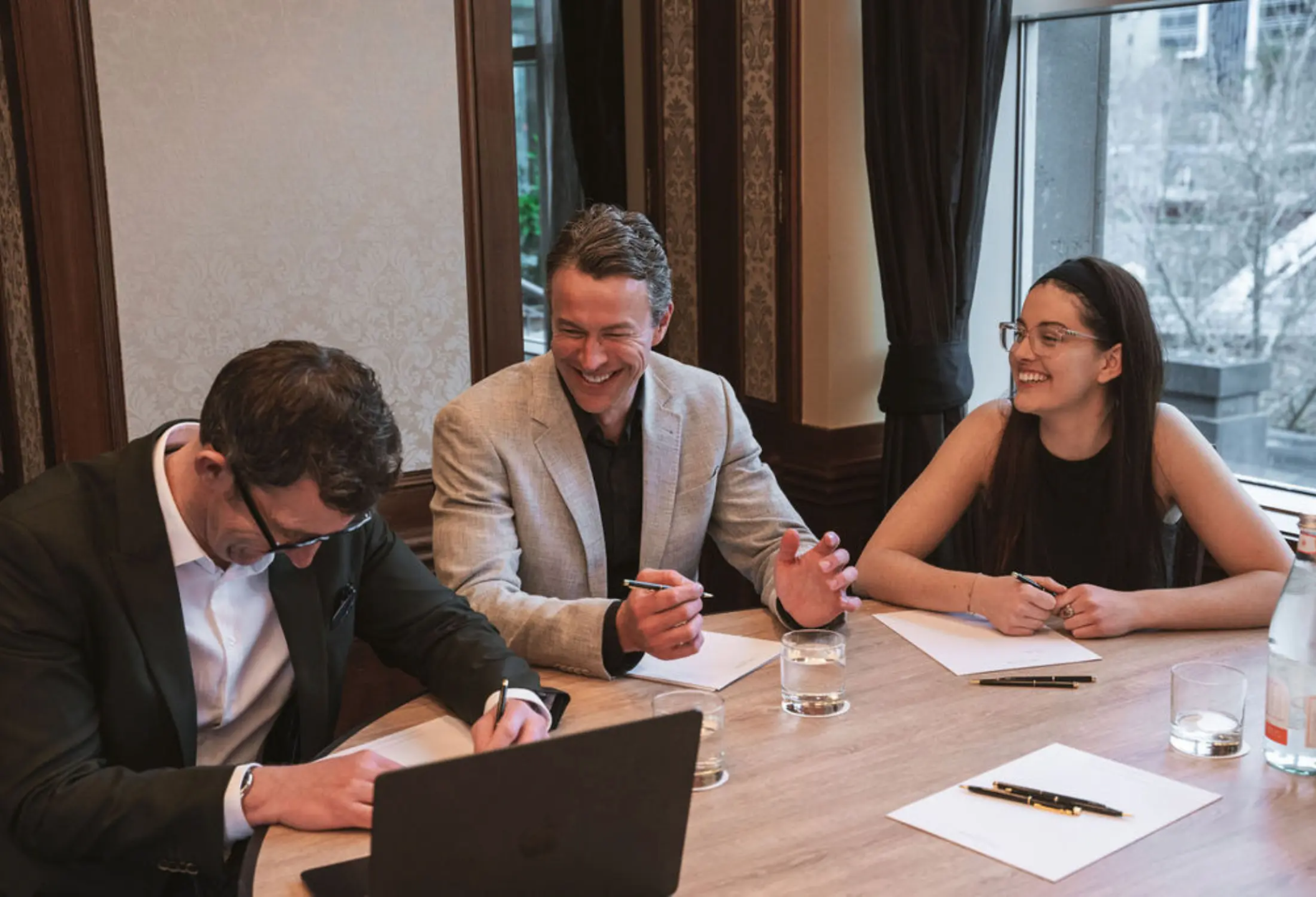 Three people sitting on a table laughing during a workshop session