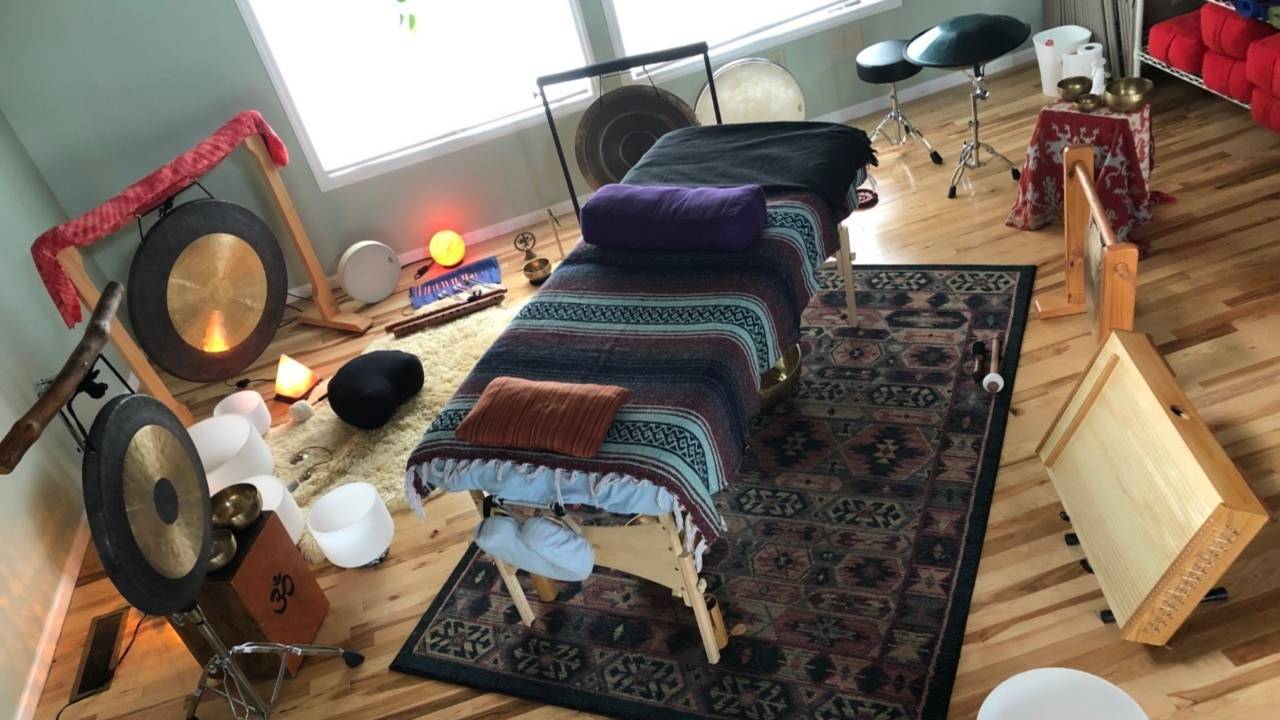 Sound Healing practitioner playing a frame drum with clients lying on mats