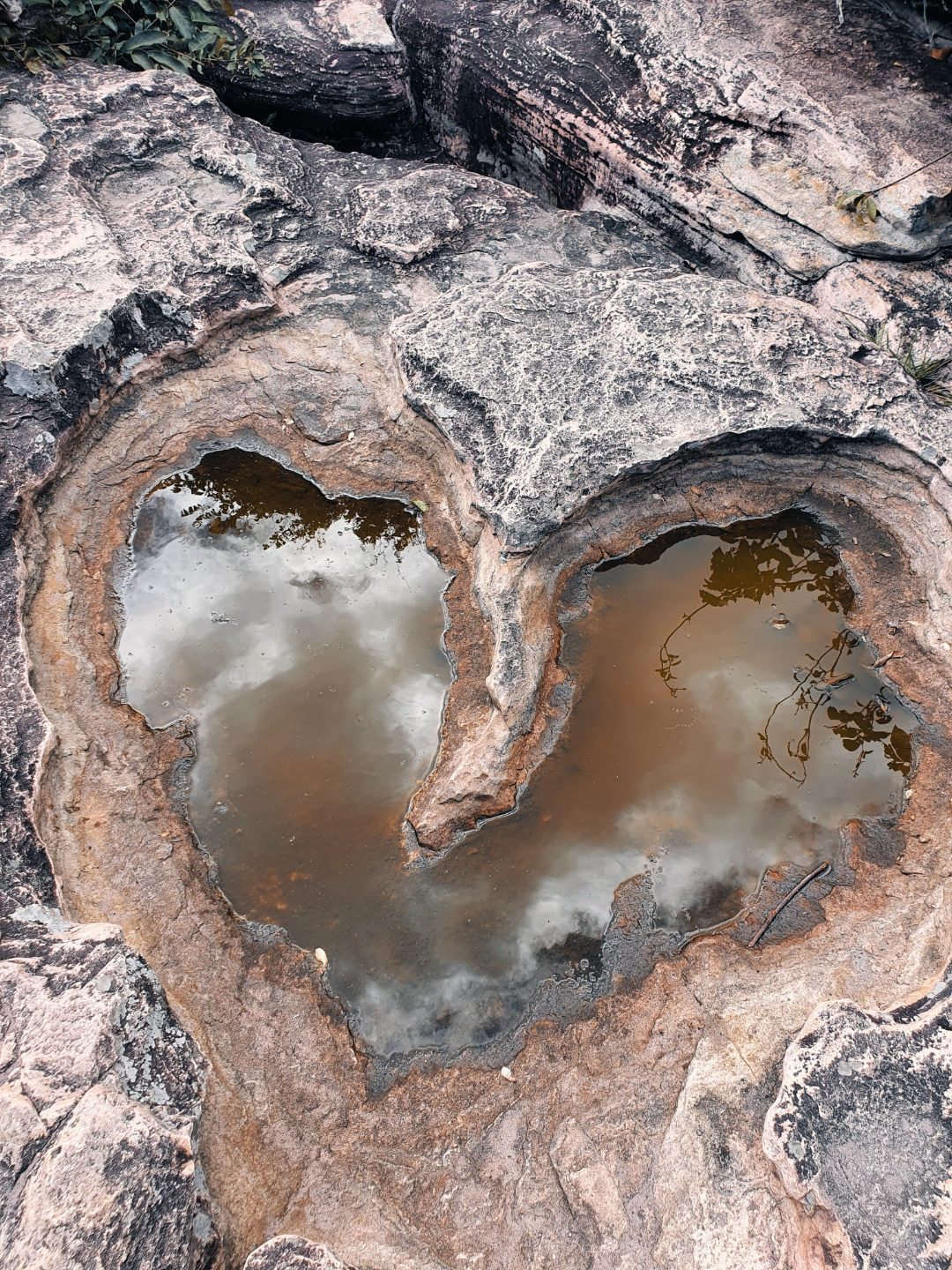 heart-shaped puddle in what appears to be volcanic rock