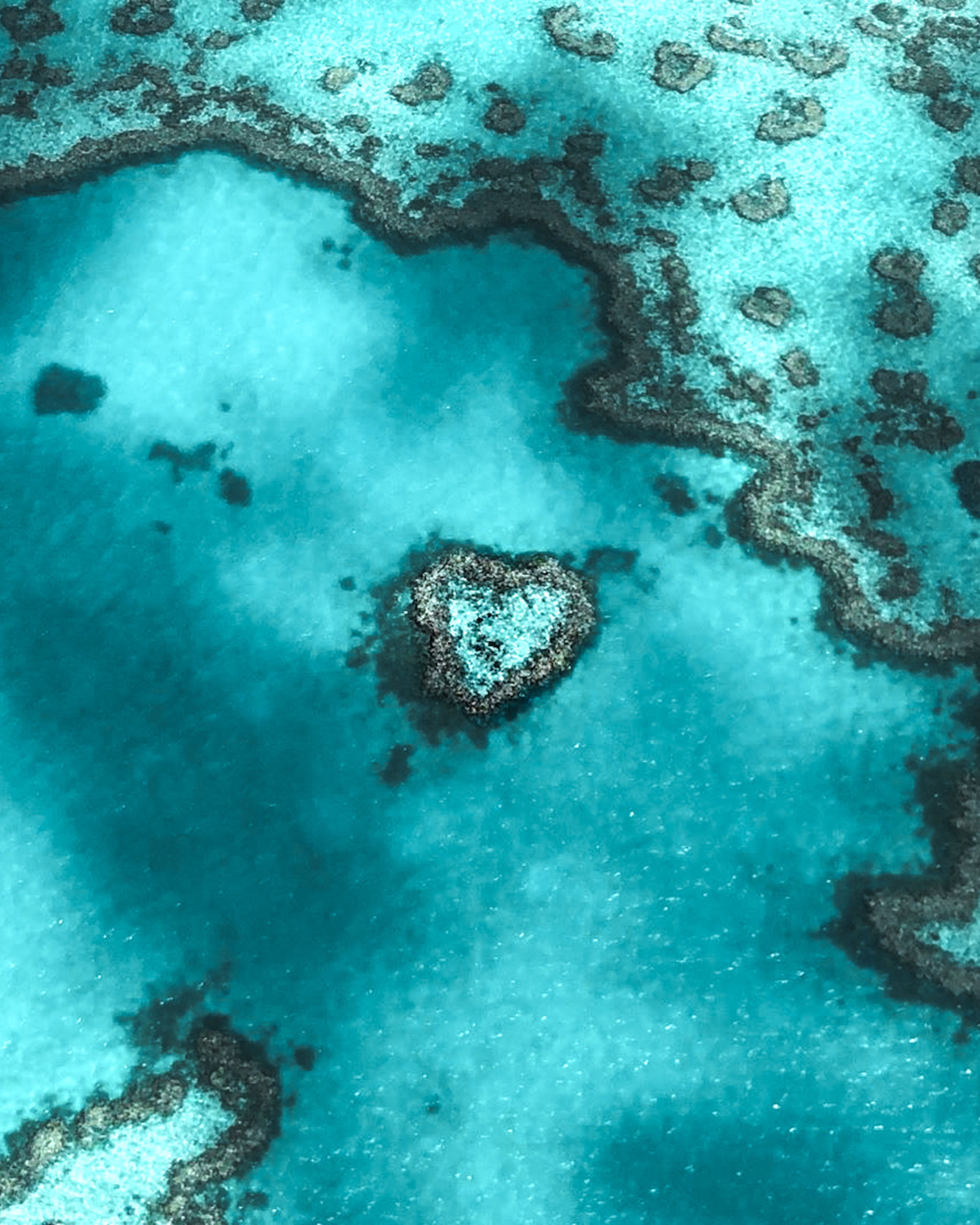 birds eye view of heart-shaped island in crystal blue waters