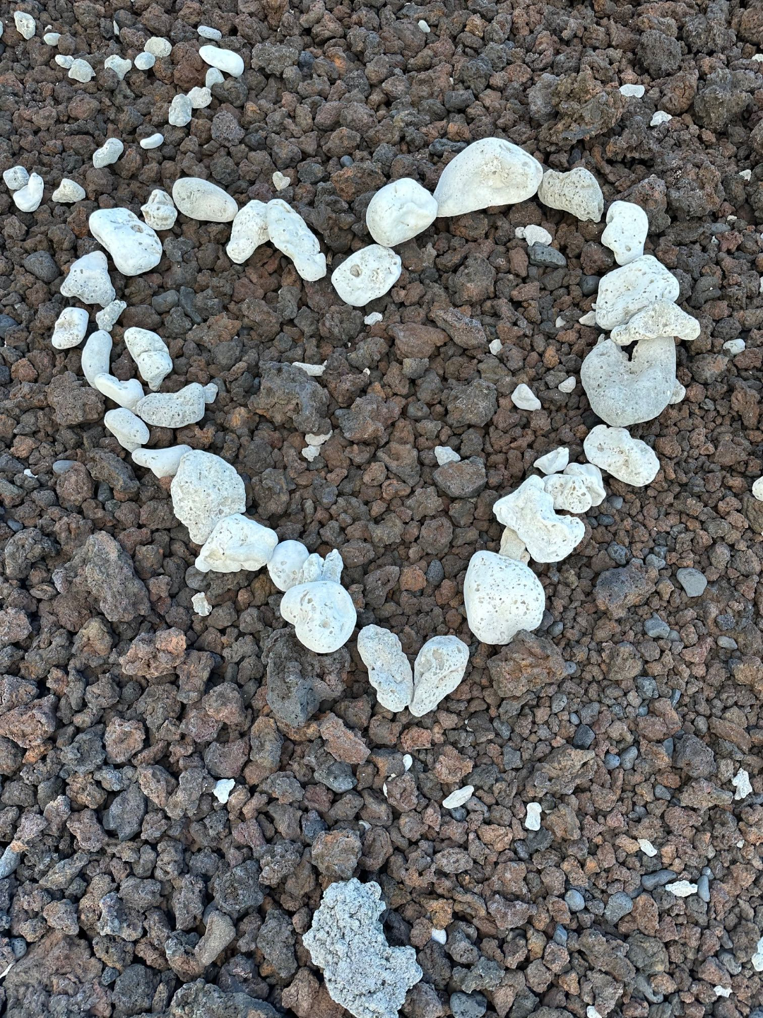 white rocks outlining a heart atop black rocks
