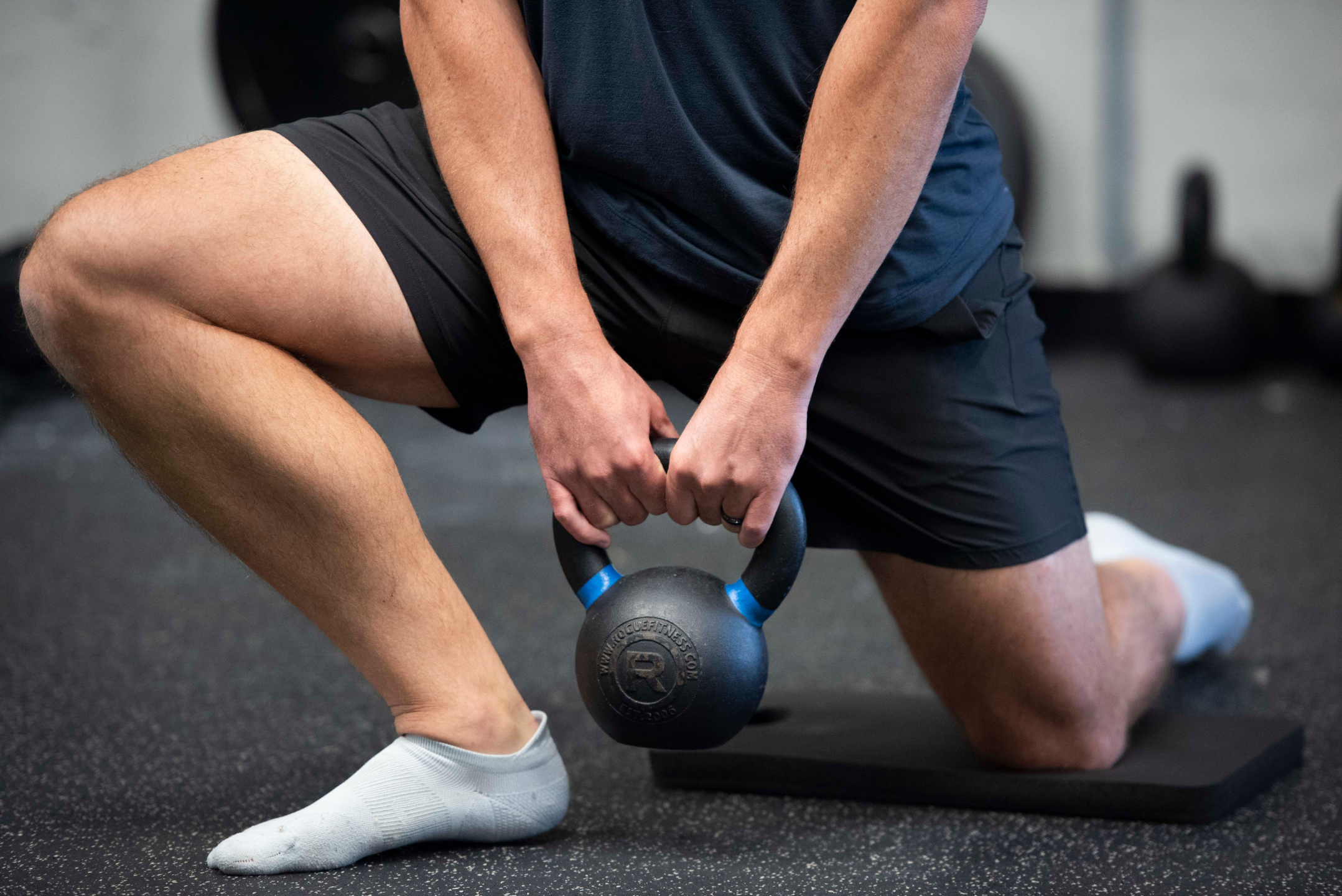 Athlete performing a kettlebell half-kneeling exercise to build strength, stability, and movement control during performance training.