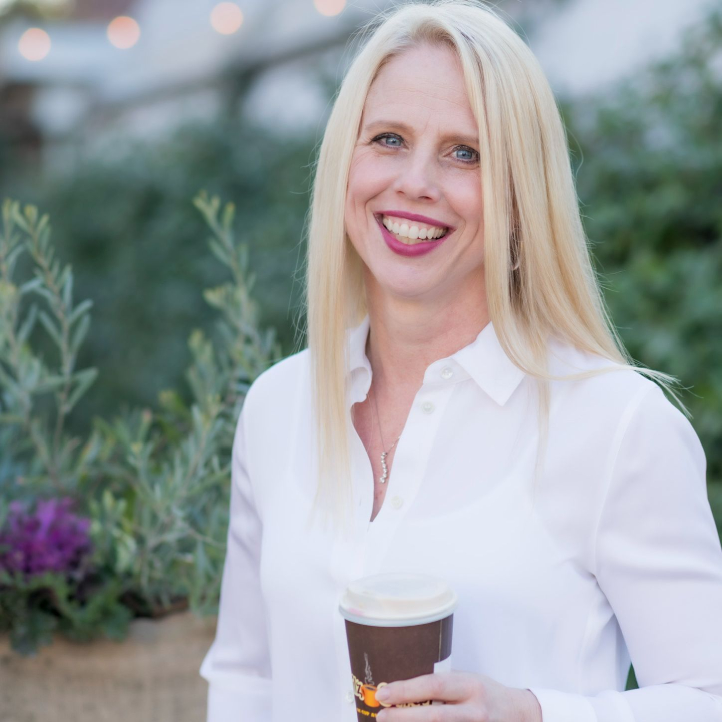 Vivian Gill holding a to-go coffee cup, symbolizing a balanced approach to wellness and life's simple pleasures.