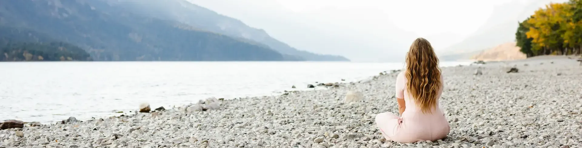 Crystal the parenting coach sitting on a rocky beach