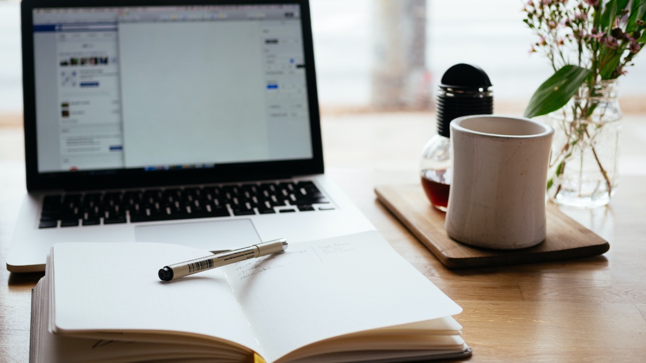 Picture of computer with notebook to take notes on in front of computer
