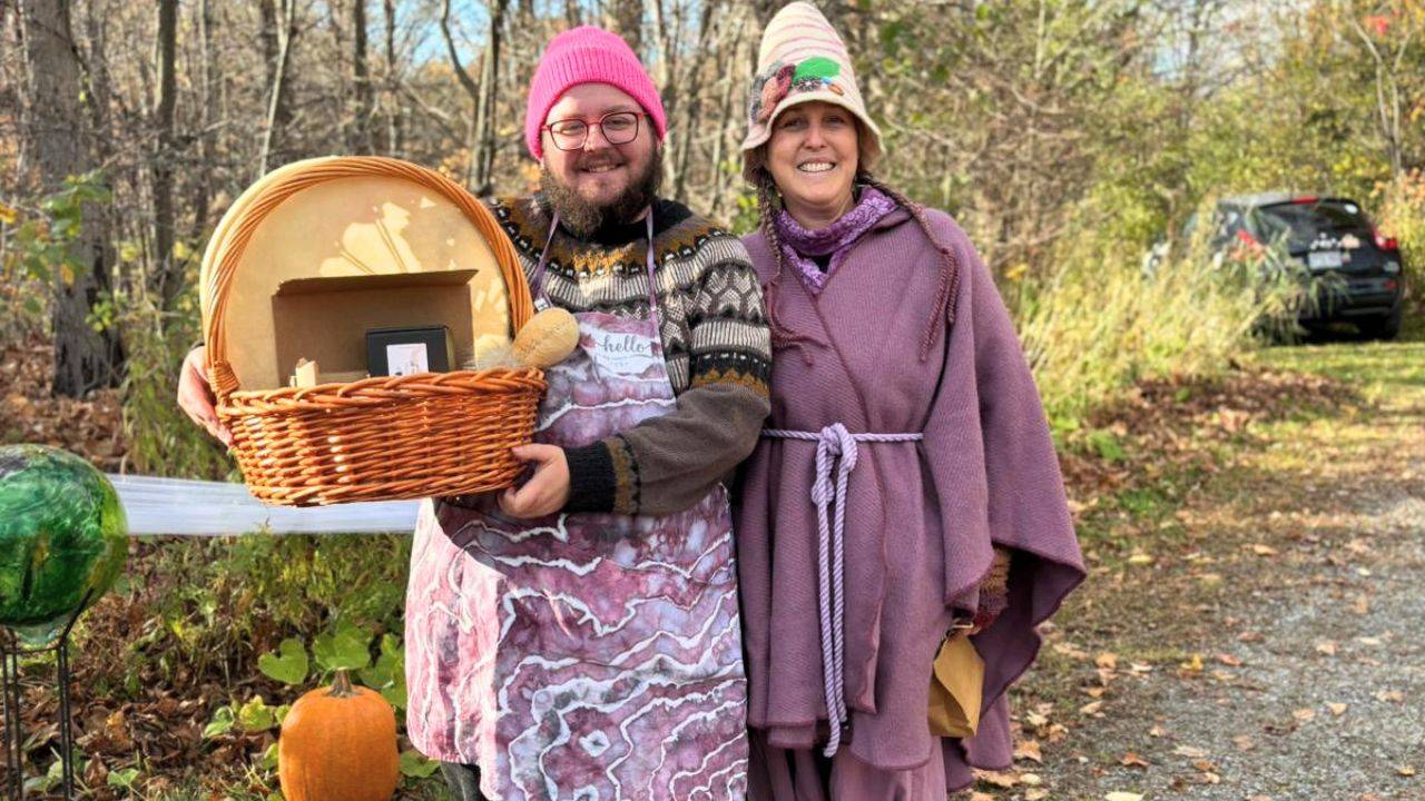 two people on a forest trail holding up a basket with gifts