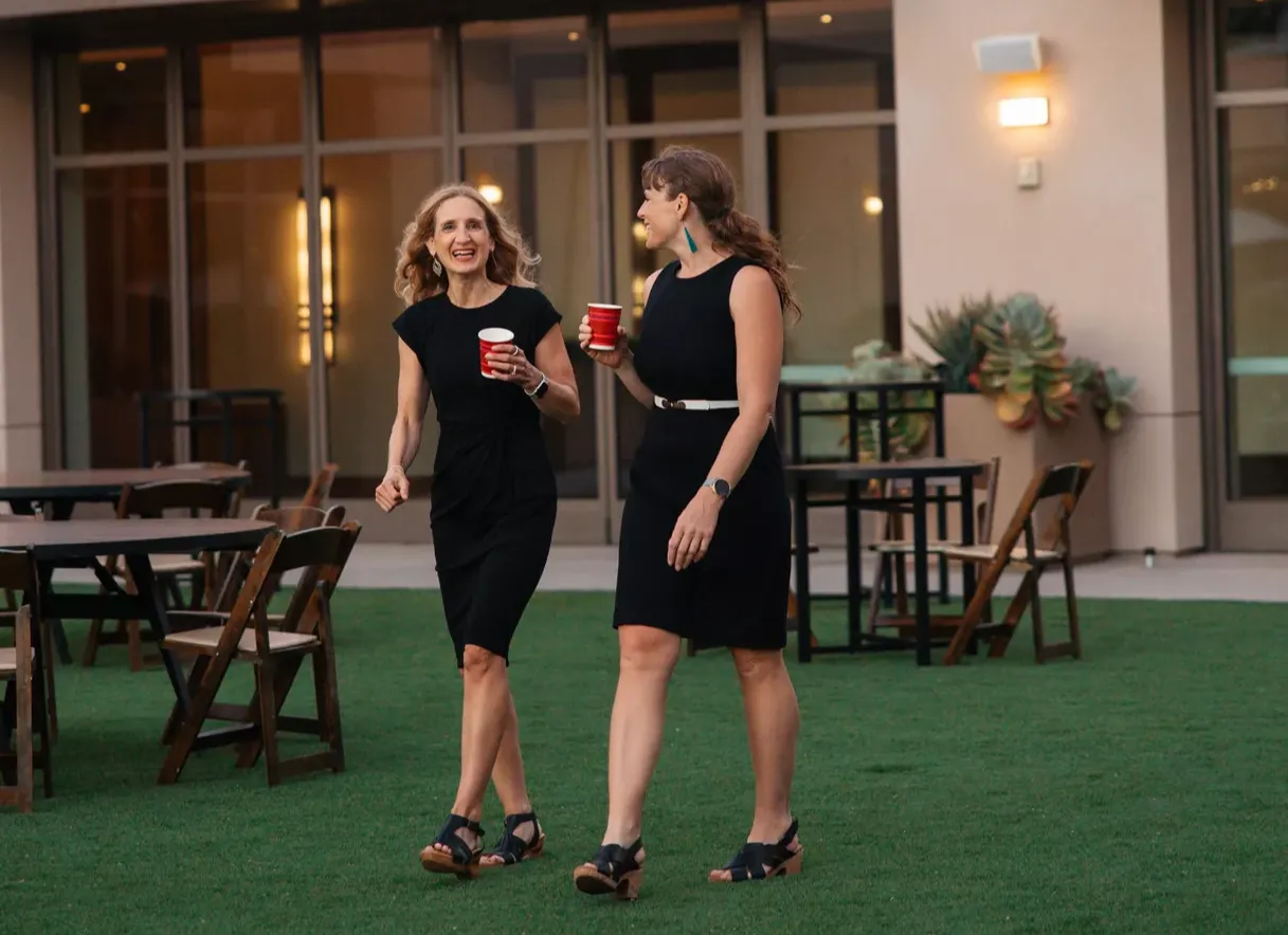 Sarah and Patrina walking holding a cup