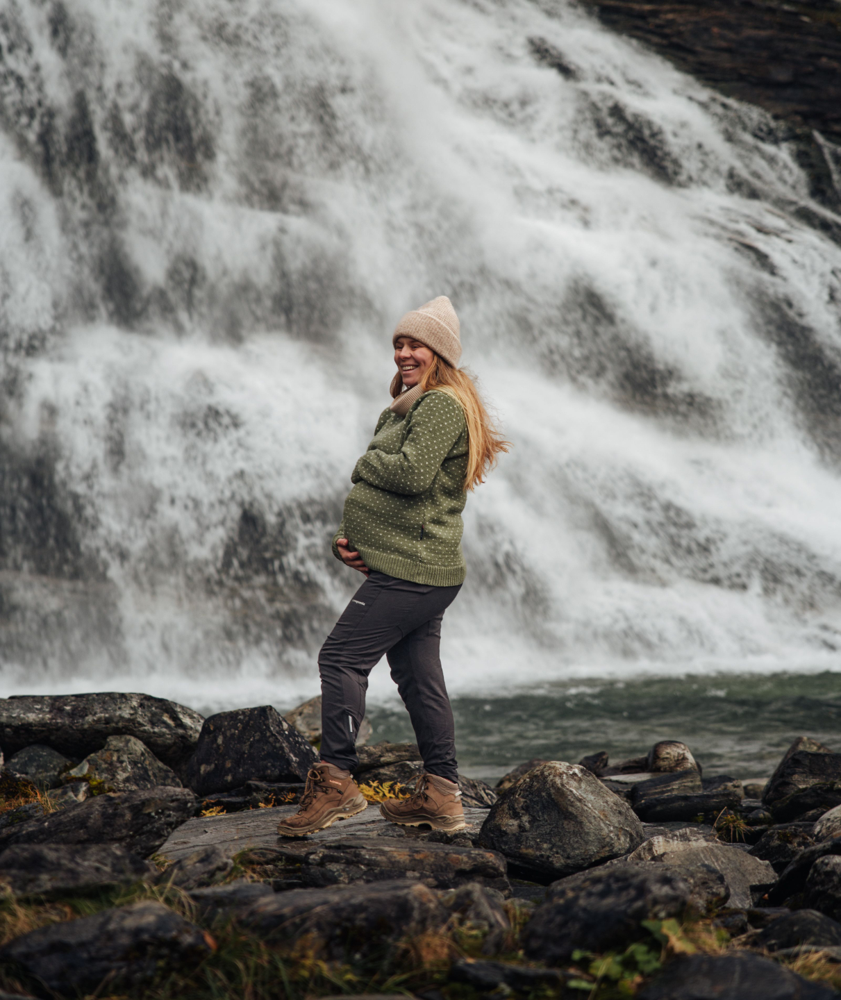 uusien äitien ja raskausajan valmentaja hymyillen ja pitelemässä raskausvatsaa