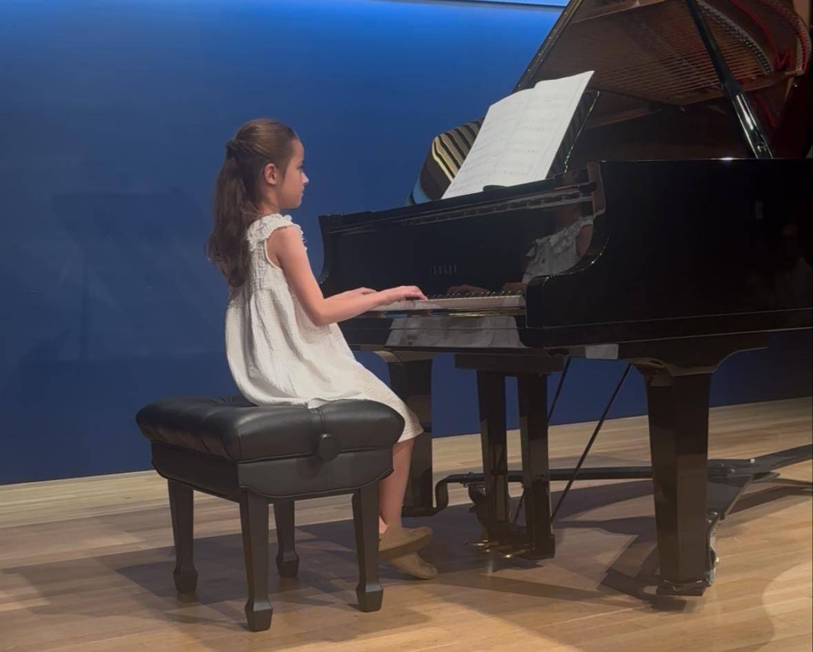 Young piano student performing at a grand piano in New York City