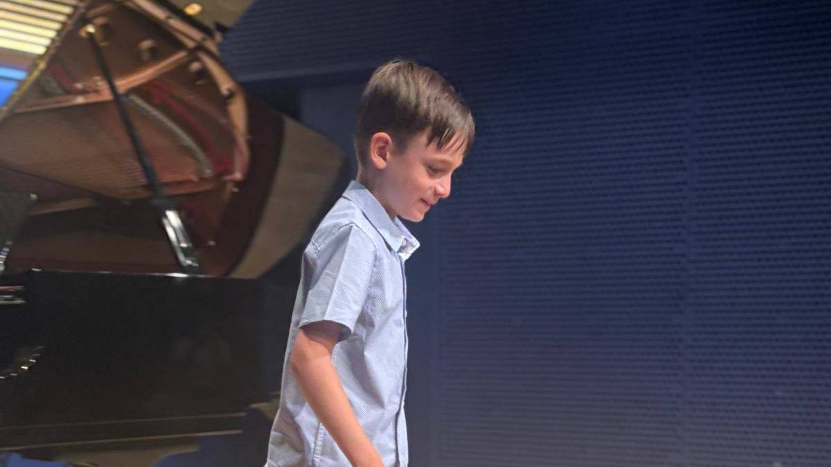 Young pianist receiving instruction from a side angle