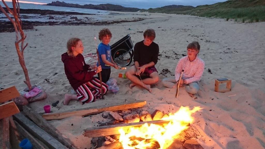 Kids having a fire on the beach.